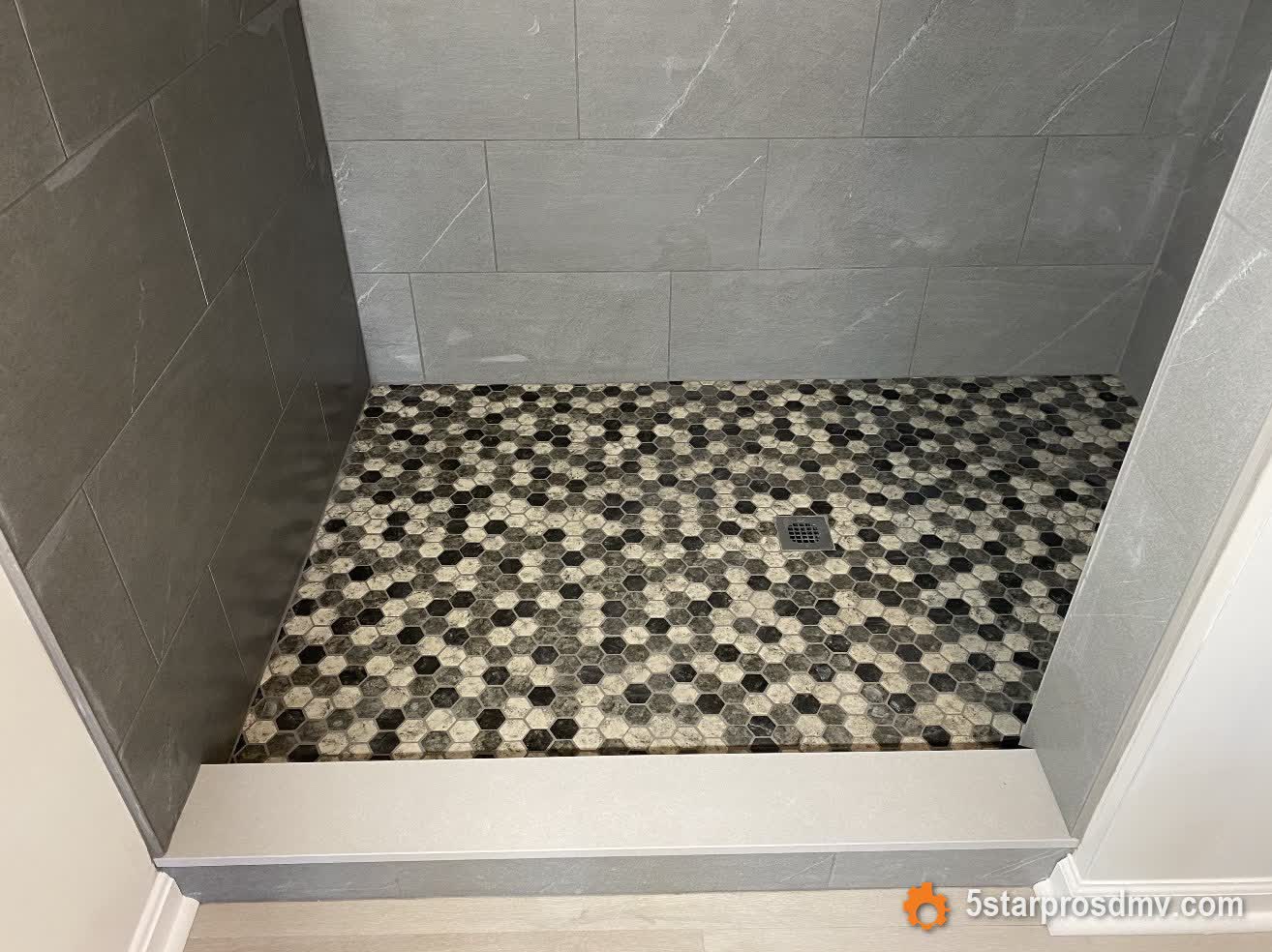 Piso de ducha con mosaico hexagonal blanco y negro y paredes símil mármol gris por 5 Star Pros DMV
