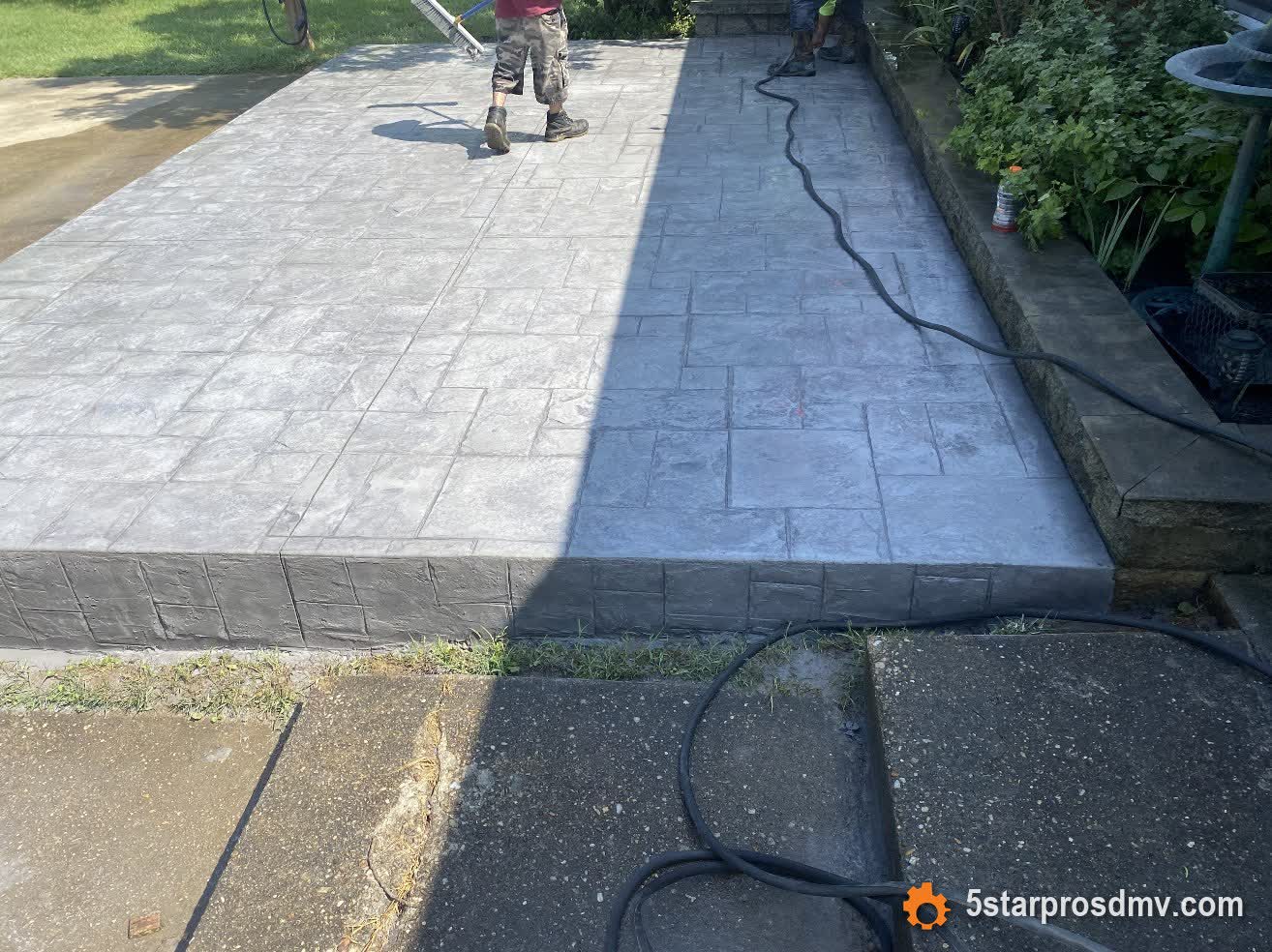 Patio de concreto estampado con acabado de dos tonos y borde de piedra siendo sellado por 5 Star Pros DMV