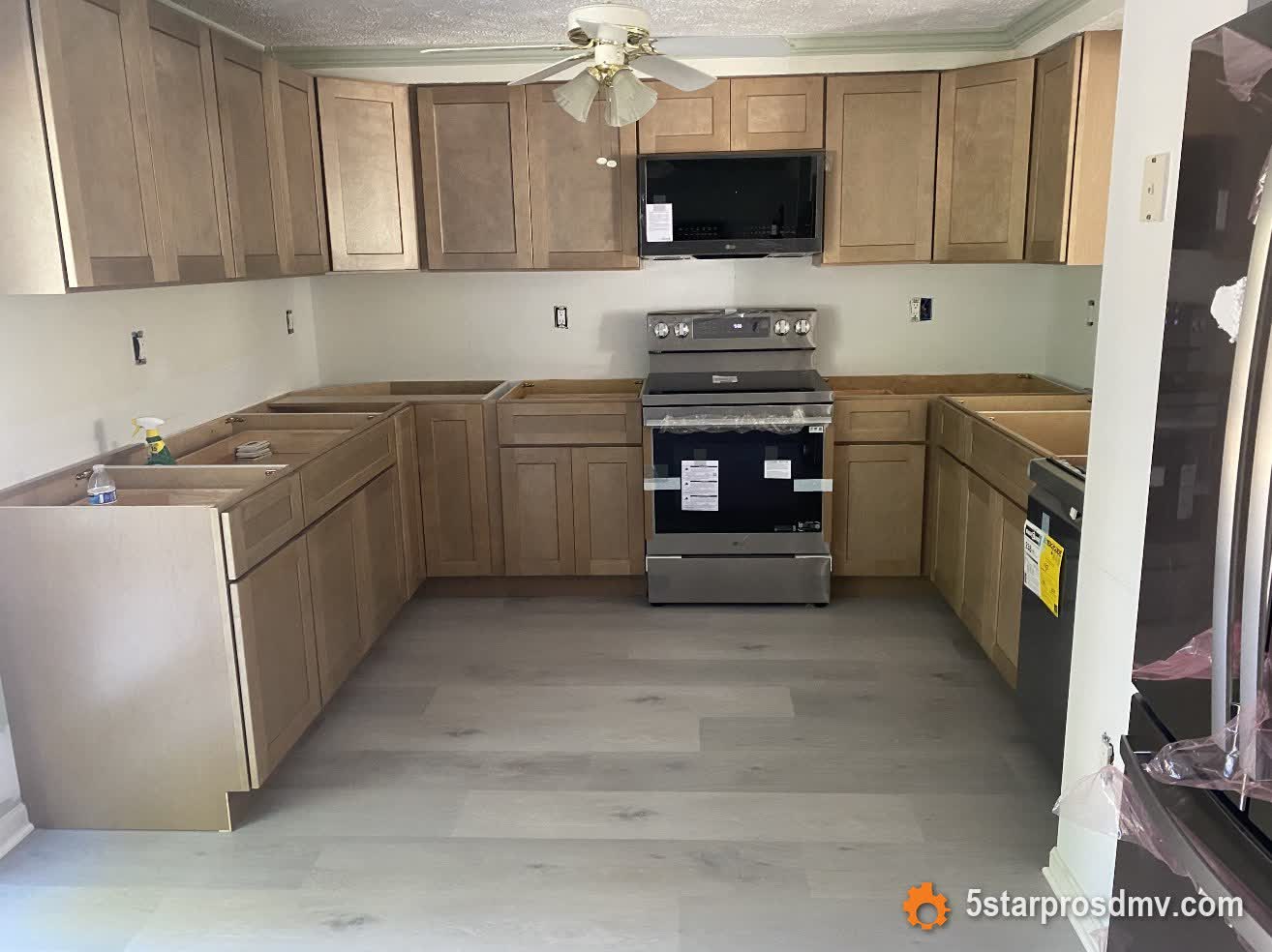 Remodelación de cocina en progreso con nuevos gabinetes de madera y piso de vinil de lujo por 5 Star Pros DMV