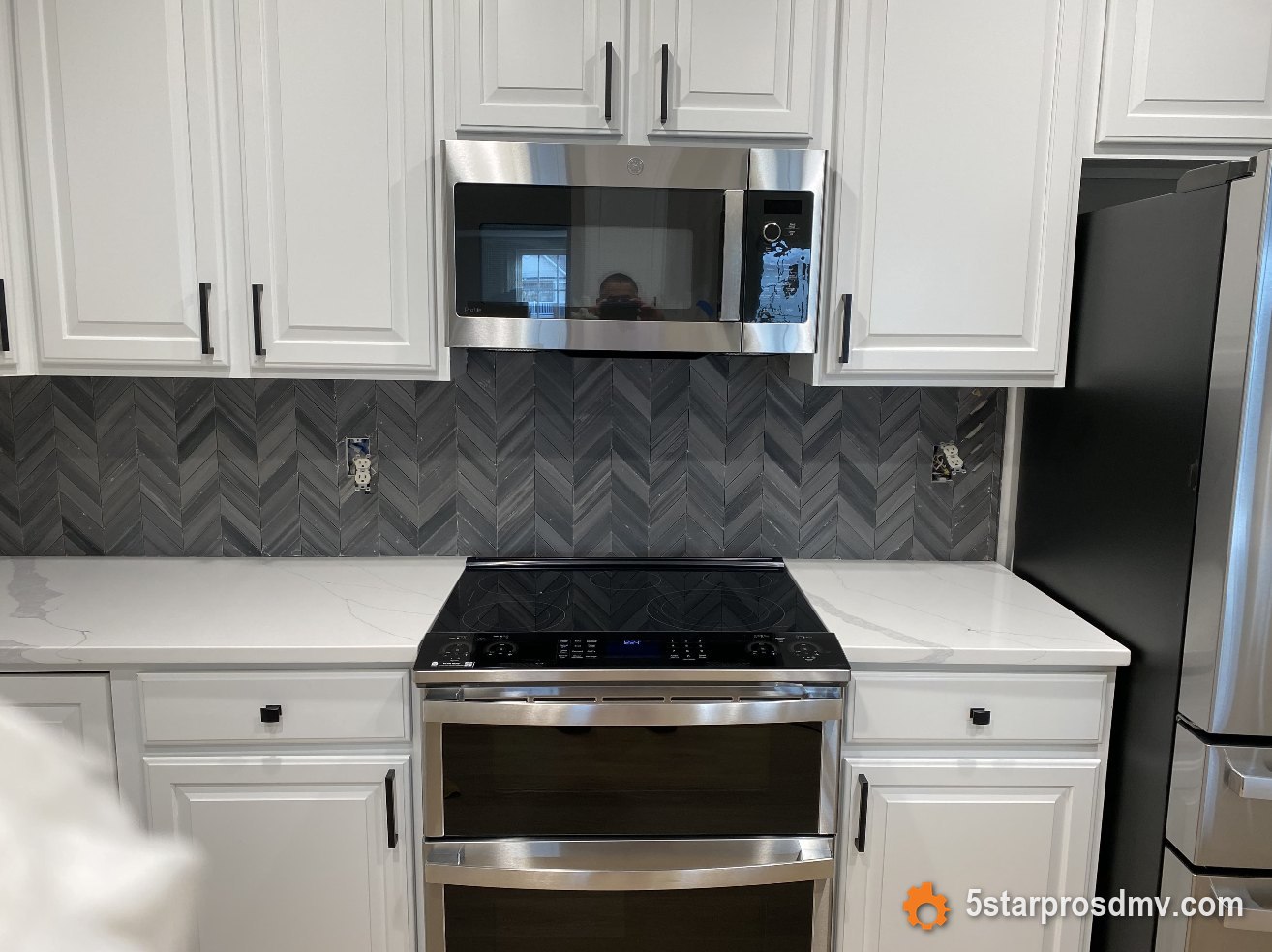 Cocina blanca estilo shaker con salpicadero chevron, encimeras de cuarzo y estufa de acero inoxidable de doble horno por 5 Star Pros DMV